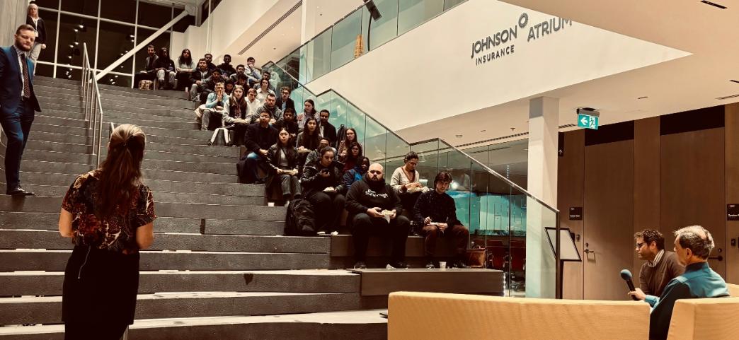 A group of students sitting on stairs listening to speaker